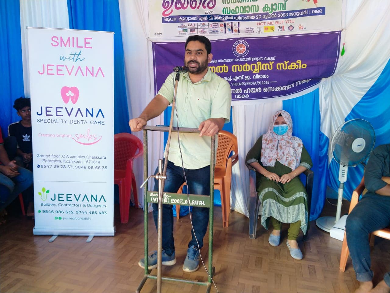 Muhammed Shahim addressing volunteers and students at the NSS Special Camp with Jeevana Dental Care banner